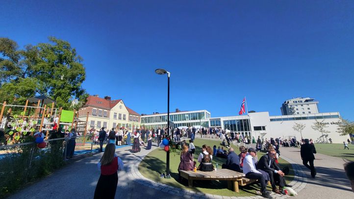 17.mai-arrangement på skolen, oversiktsbilde av festkledde mennesker tatt fra innkjørsel.
